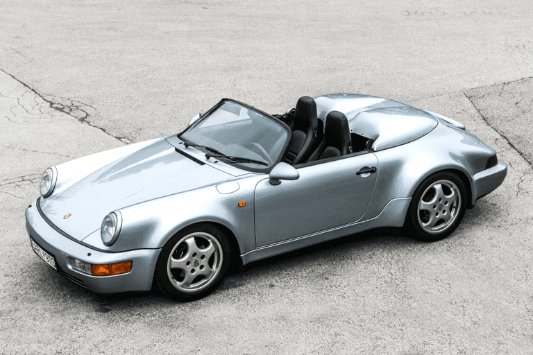 Silver Porsche 911 Speedster with open roof on concrete pavement