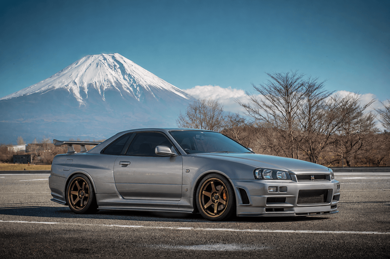 Silver Nissan Skyline GT-R R34 beneath Mount Fuji